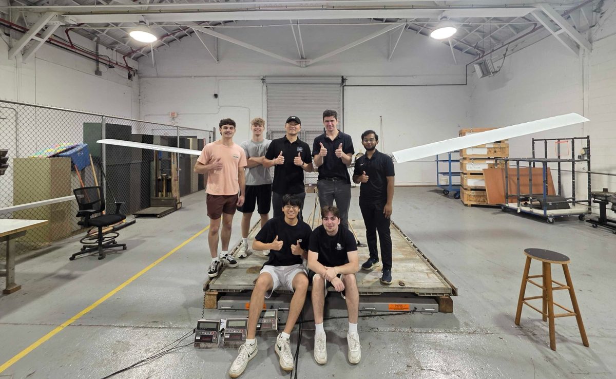 Seven team members with the aircraft on a weighing platform in a hangar